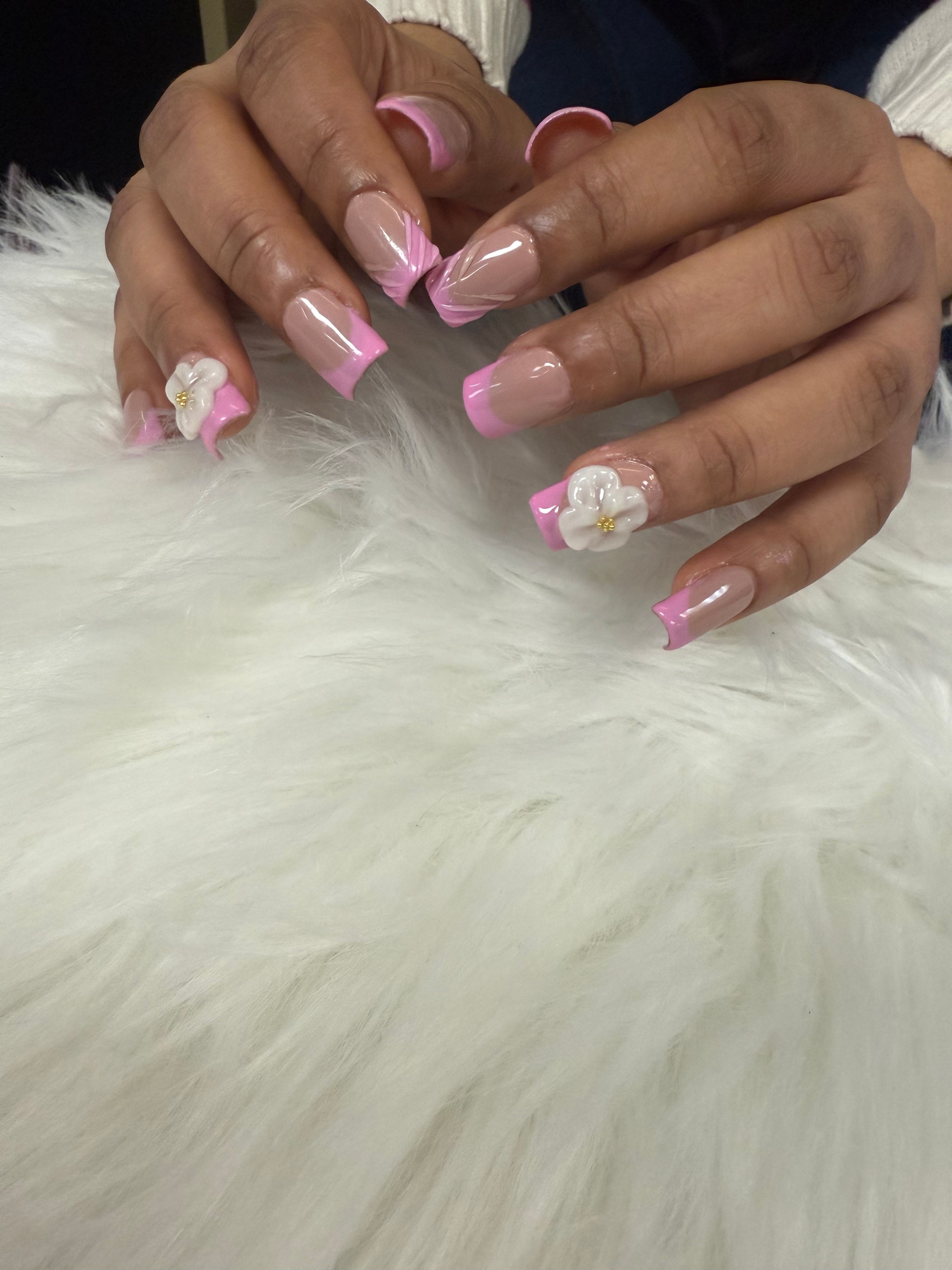 Pink French tip nails with white floral 3D accents