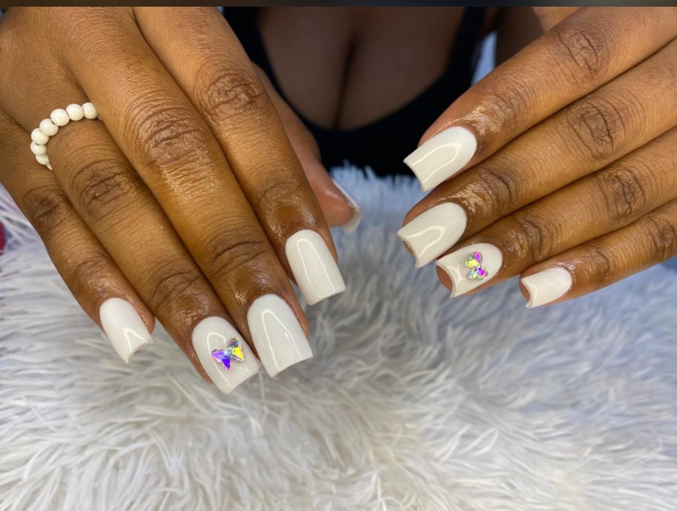 White nails with floral and butterfly crystal embellishments
